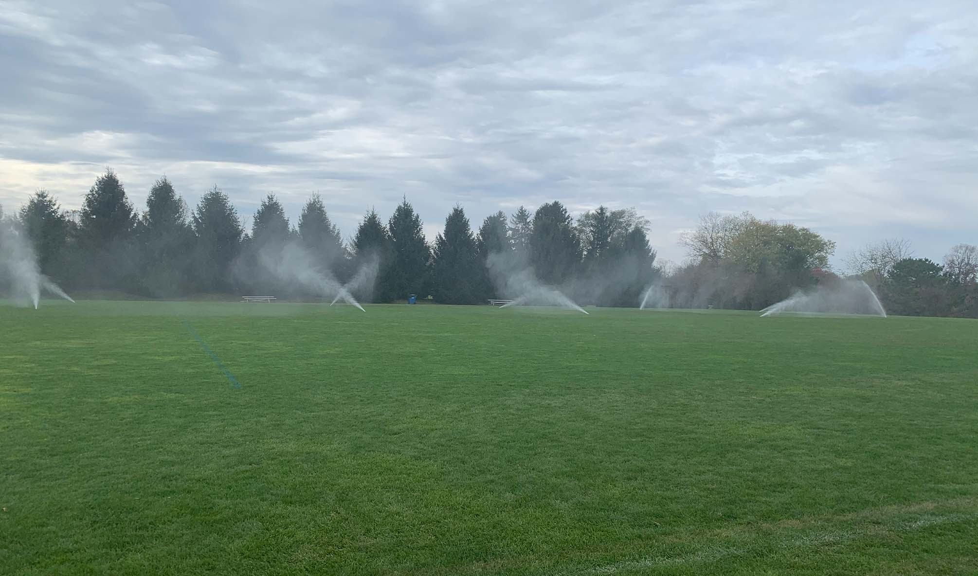 Irrigation Sprinklers Set To On in A Large Grass Field