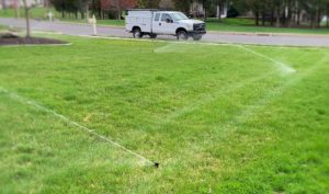 Truck Parked Next to a Lawn Getting Watered