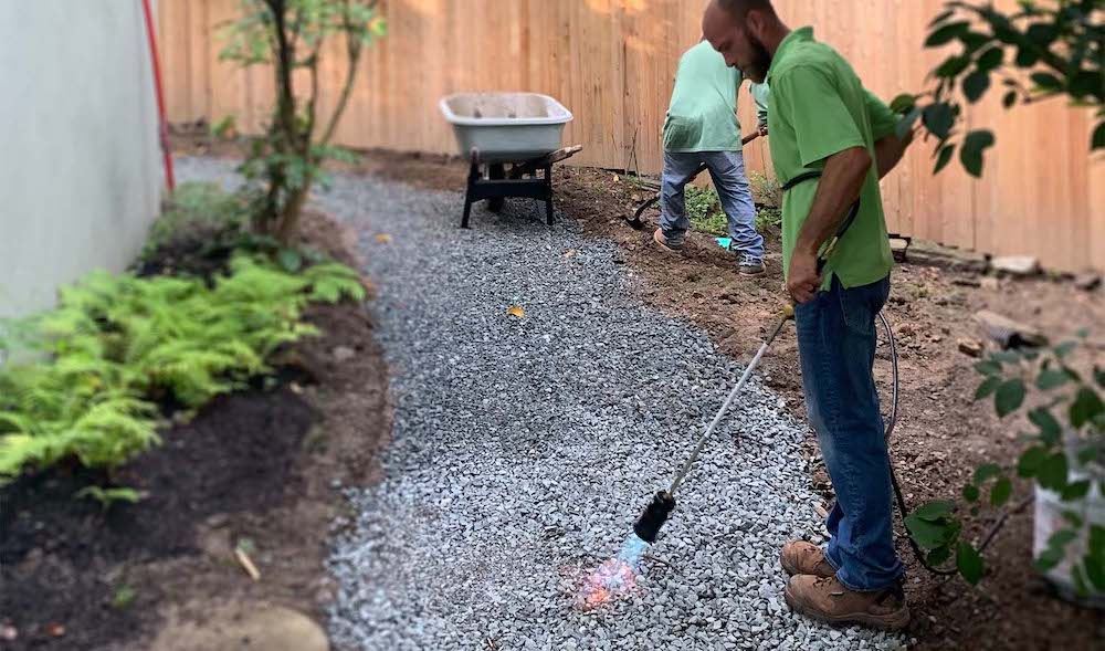 Workers Doing A Porous Path In A Backyard Along A Fence